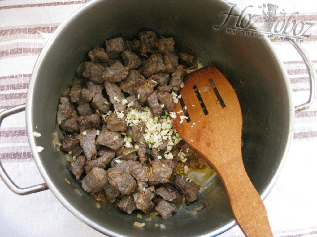 Переложите мясо в кастрюлю и добавьте чеснок