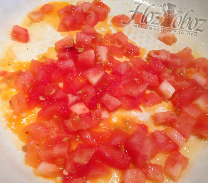 Нарезанный томат выкладываем на разогретую сковороду с оливковым маслом и чесноком. Если чеснок уже поджарился, его следует предварительно извлечь
