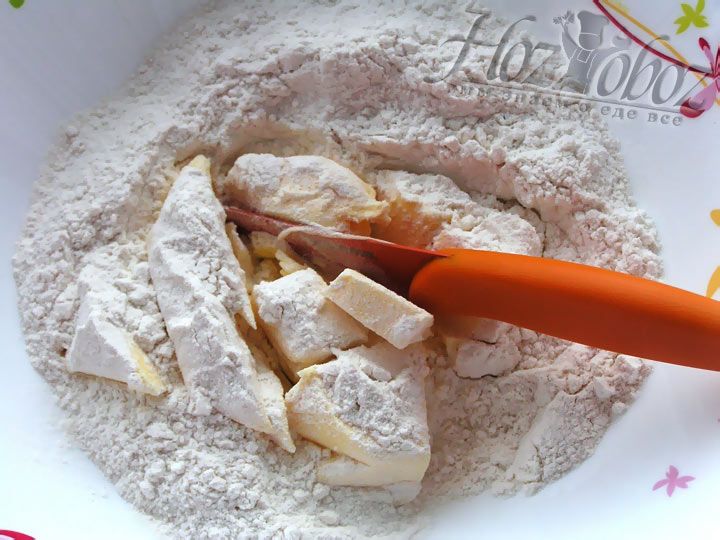 Для песочного теста необходимо порубить ножом в миску замороженное сливочное масло, а затем пересыпать его мукой, чтобы получить масляную крошку