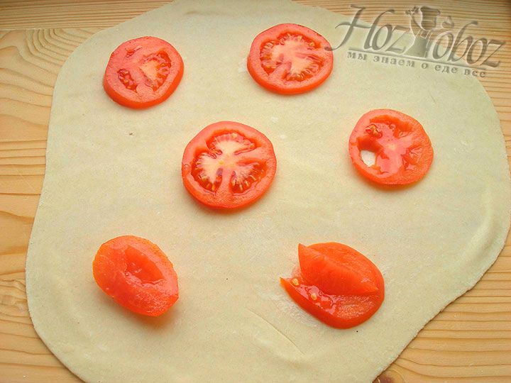 Готовое тесто делим пополам и из половины раскатываем тонкий пласт. На поверхности теста на расстоянии 3-4 см друг от друга размещаем томаты