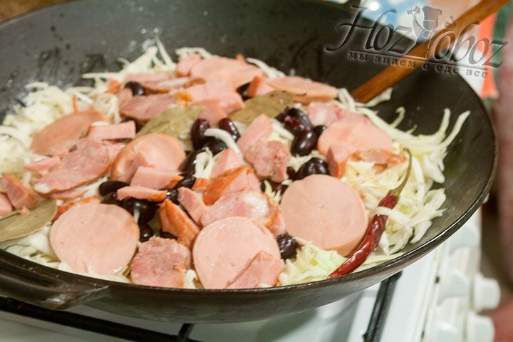 На капусту помещаем окорок, домашнюю запеченную колбасу, а также отваренные в бульоне кусочки колбаски вареной