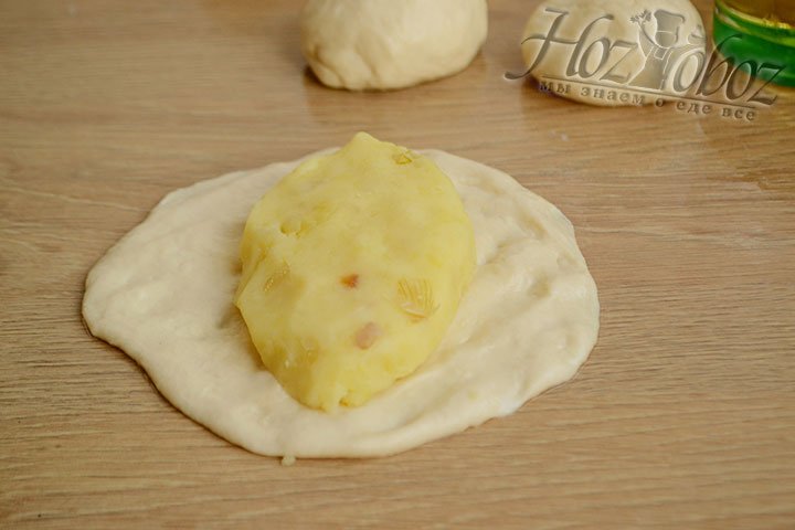 Из шарика теста пальцами на смазанной маслом поверхности формируем лепешку и кладем на нее картофельную начинку.